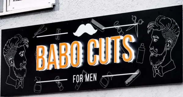 Außenschild Barbershop mit orangem Leuchtschriftzug und Bart Icons